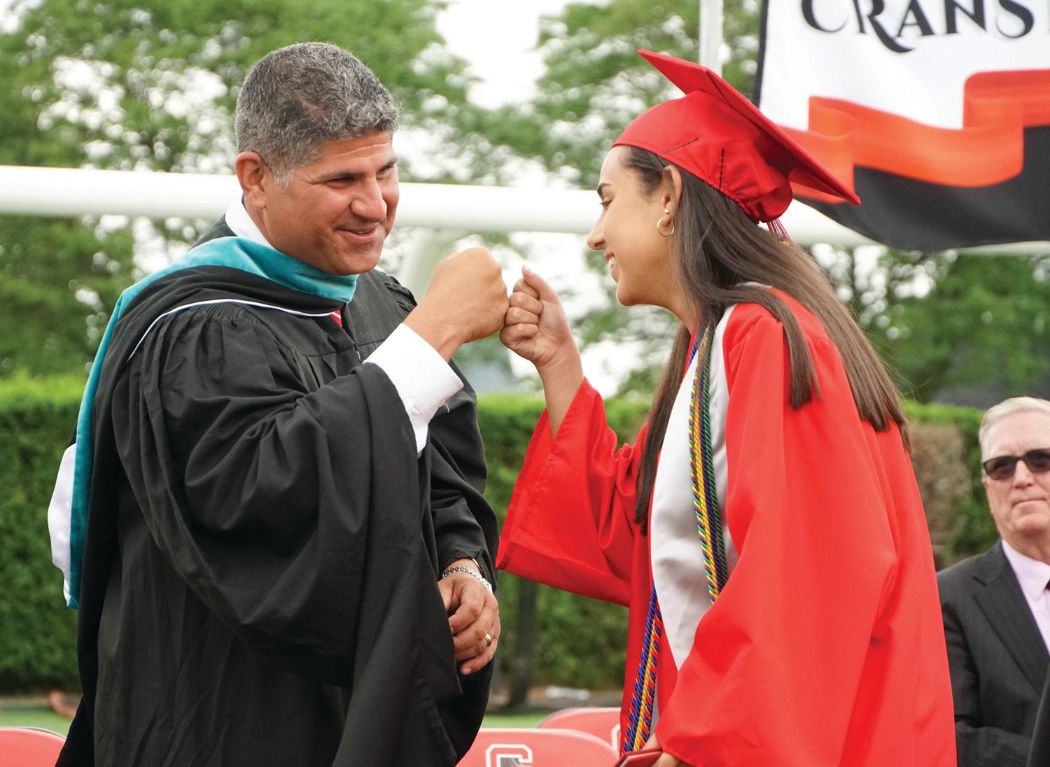 FALCONS SOAR: Above, Cranston West class of 2021 salutatorian and Ideal Cranstonian Catherine Consiglio fist bumps with Principal Thomas Barbieri after receiving her diploma at Saturday’s graduation ceremony.